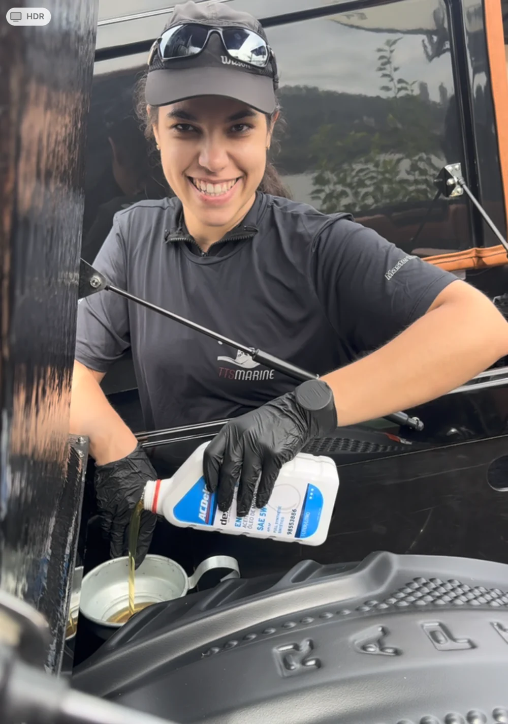 Isabela colocando óleo no motor de uma embarcação durante a manutenção na TTS Marine
